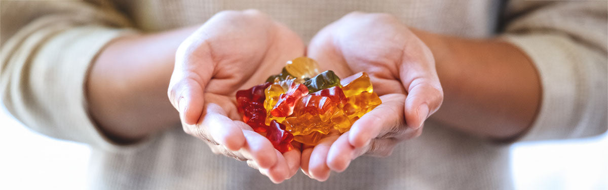 Two hands holding mushroom gummies
