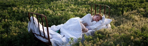 woman sleeping on a bed in a field