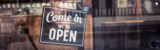 come in we're open sign in a coffee shop window