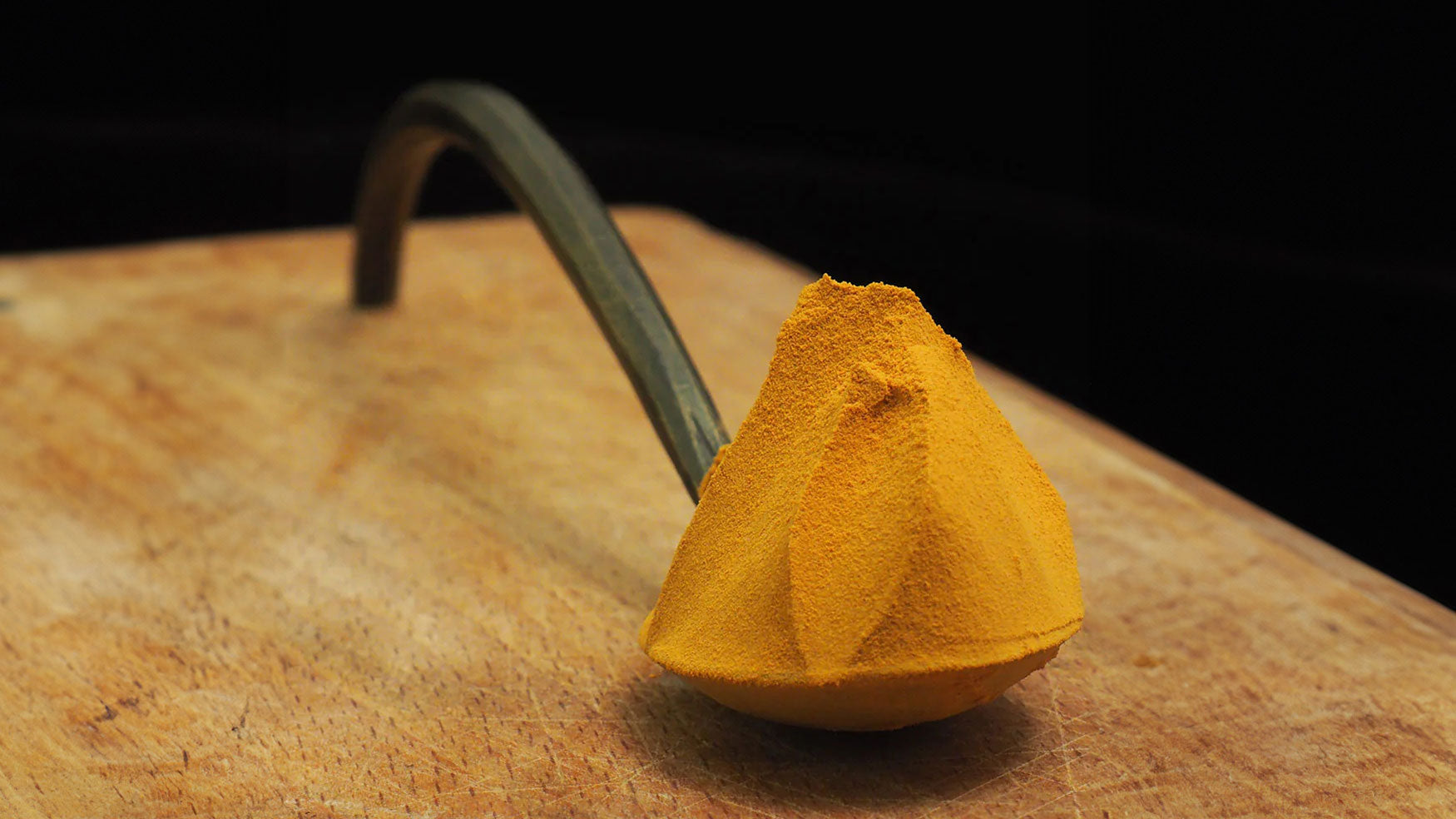Golden extract powder piled high on a handmade metal spoon